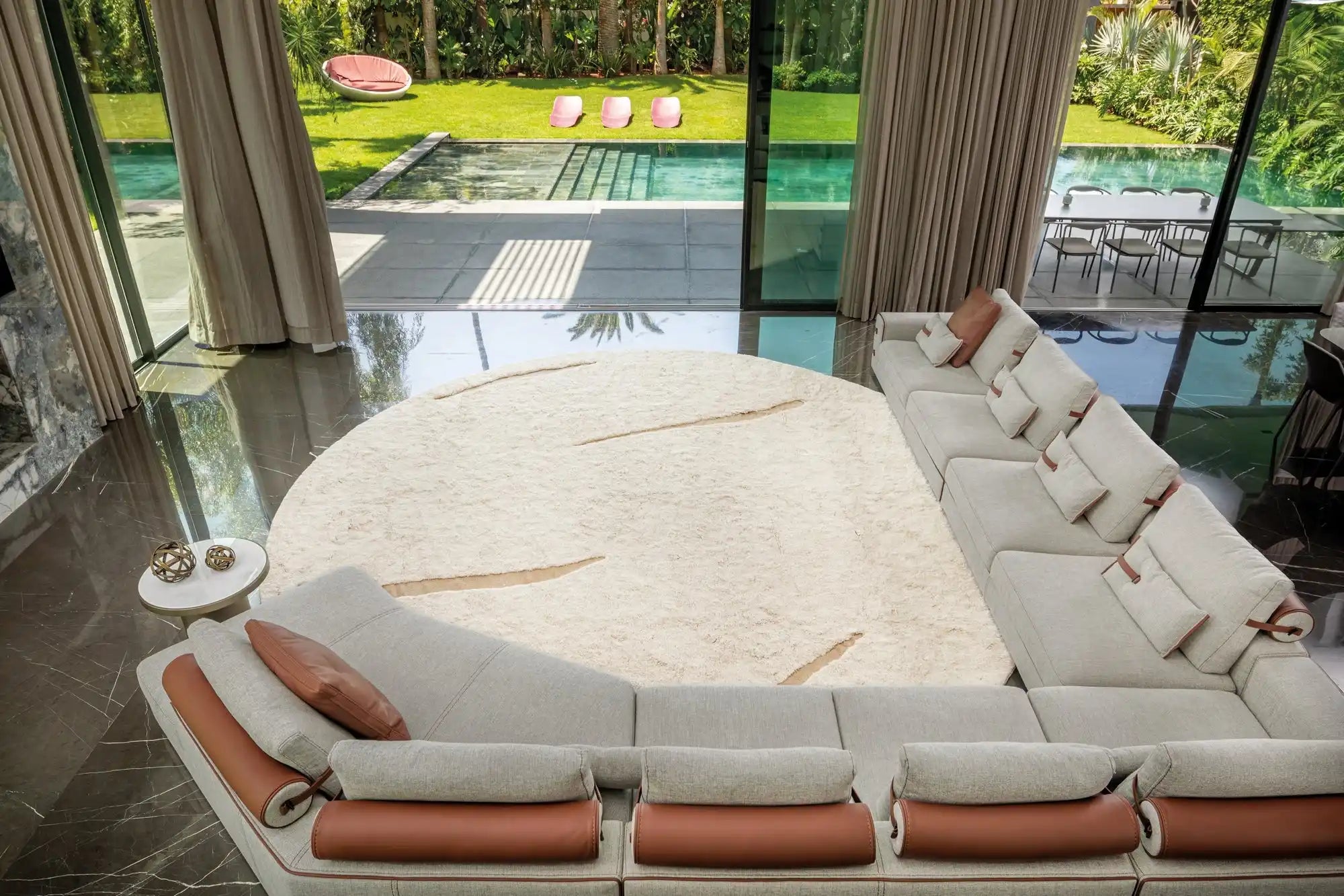 Curved sectional sofa with white cushions and brown leather accents.