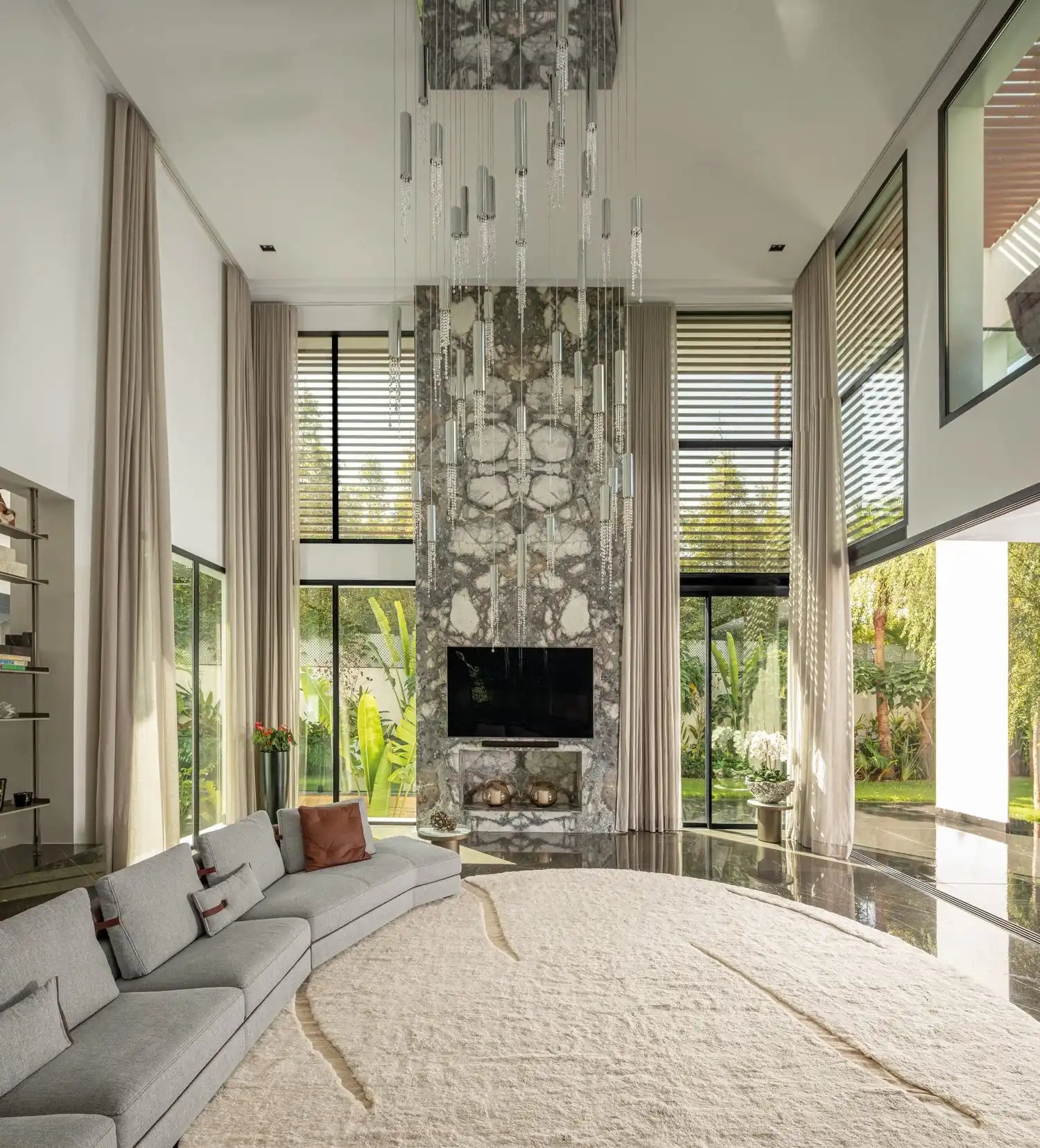 Modern stone fireplace with a mounted TV and dramatic hanging crystal chandelier.