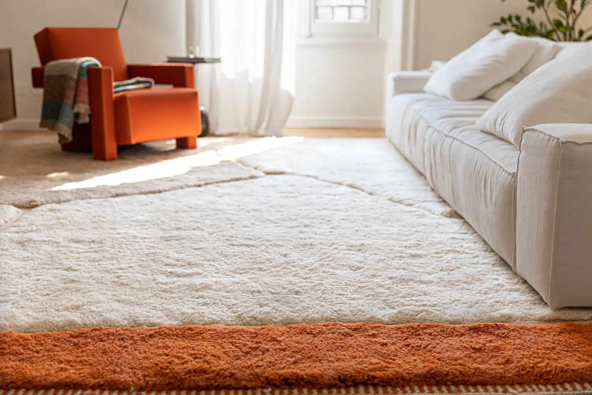Plush cream-colored area rug with an orange border.